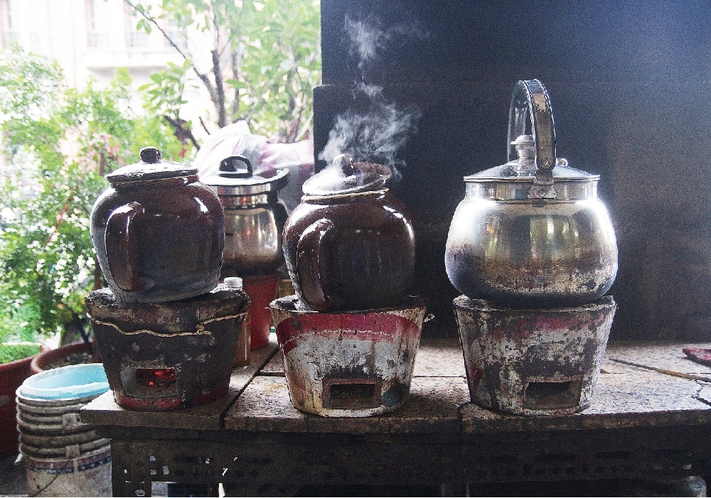 台北市萬華區的剝皮寮附近，有處耑代客煎藥的老中藥行，「耑」：專的古字， 依循古法煮藥。湊近一睹，簡易的鐵製桌台上四只竄著紅焰與白煙的火盆子，一旁挨著位年約六十的老伯，時而彎低身子察看炭火，時而搧動著手裡拏的扁塑膠扇，一會兒快而短促、一會兒慢而長緩，目珠定定地顧著爐火，頗是耗神，這專注的模樣讓我想起數年前，因為爸爸的背疾，也能在家中看見媽媽燉煮藥草，那時廚房裡總漫著濕熱的氣味，久久不散。 | 甘樂誌 | 甘樂文創 | 甘之如飴，樂在其中