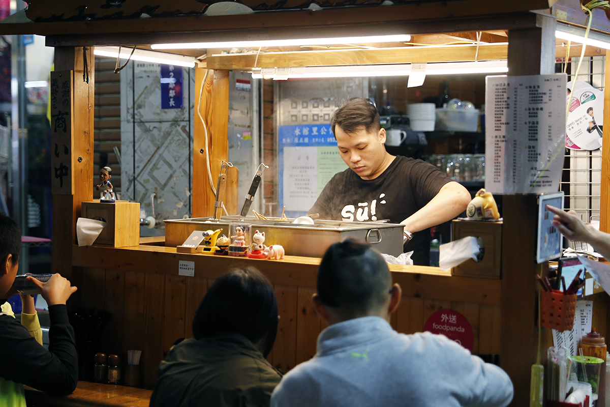 小店就坐落在街道上，幾張桌椅和吧台區，用餐時間馬上就坐滿了客人，大家絡繹不絕地聊著日常發生的事情，點著一盤關東煮，喝上兩三碗湯，「湯，可是我研究很久才做出來的，嘗試不同的配方和熬煮的時間，現在這個版本可是熬了三個小時喔！」 | 甘樂文創 | 甘之如飴，樂在其中